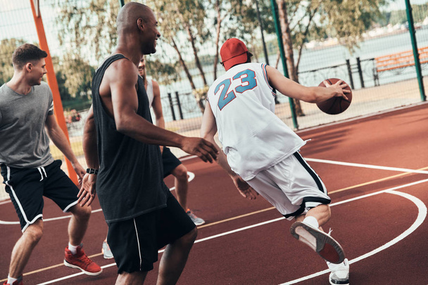 group of young men in sports clothing playing basketball outdoors - Photo, image