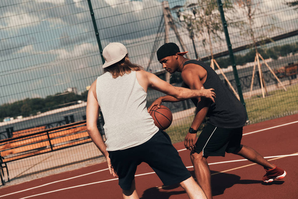 two friends playing basketball outdoors on basketball arena court - 写真・画像