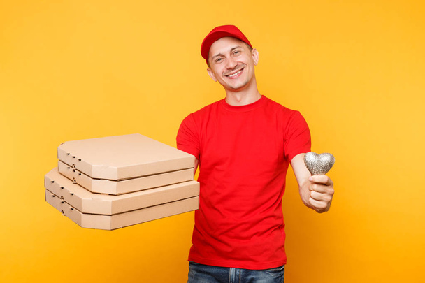 Delivery man in cap t-shirt giving food order pizza boxes isolated on yellow background. Male employee pizzaman courier in uniform holding heart italian pizza in cardboard flatbox. Service concept - Photo, Image