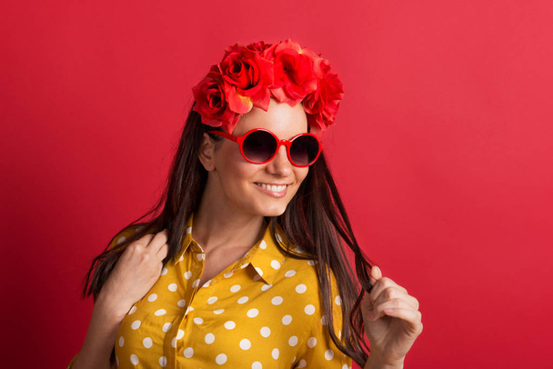 A young woman in studio with sunglasses and red flower headband. - Photo, image