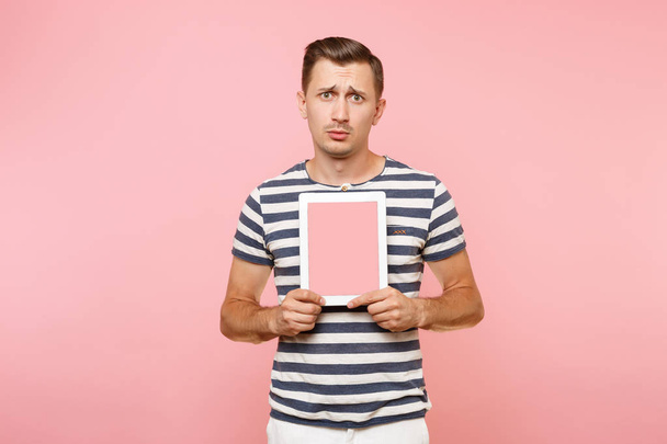 Портрет молодого чоловіка, який тримає планшетний комп'ютер з порожнім чорним порожнім екраном, відображає простір для копіювання, ізольований на тренді пастельно-рожевого фону. Технологія концепції способу життя. Рекламна зона
 - Фото, зображення