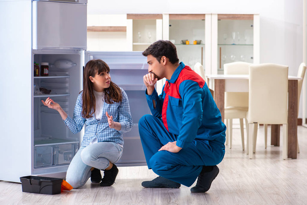 Man repareert koelkast met klant - Foto, afbeelding