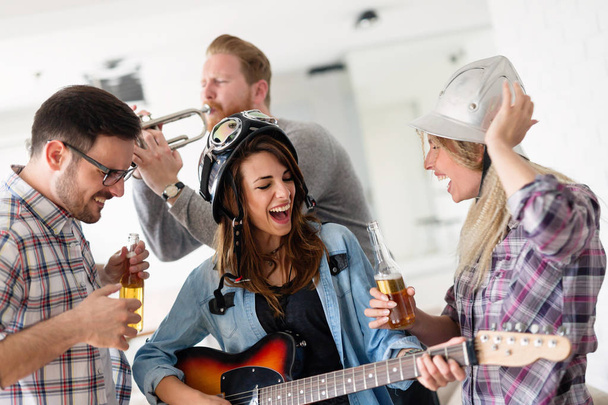 Cheerful happy group of friends having fun while playing instruments and drinking - 写真・画像