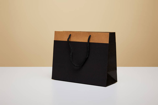 one black shopping bag on white table - Fotoğraf, Görsel