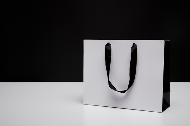 one white paper shopping bag on white table isolated on black - Foto, Imagem