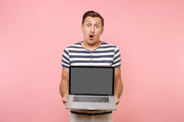 Retrato de un hombre joven sosteniendo en la computadora portátil de la mano con pantalla vacía en blanco espacio de copia de pantalla vacía aislado sobre fondo rosa pastel. Gente emociones sinceras concepto de estilo de vida. Área publicitaria
 - Foto, imagen