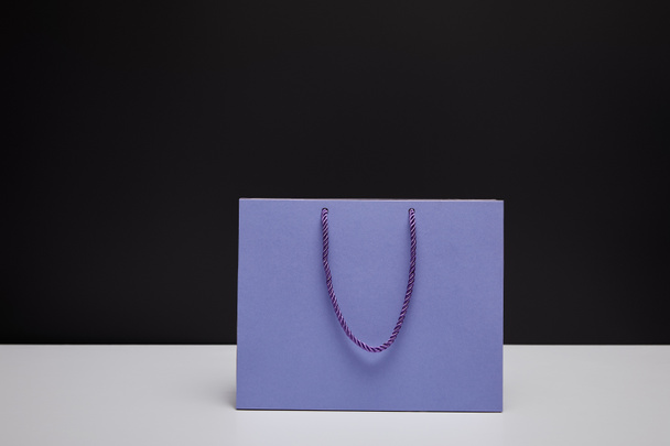 one violet shopping bag on white table isolated on black - Photo, Image