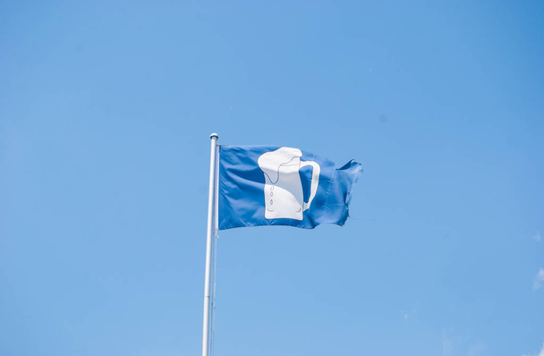 Синее развевающееся знамя со стаканом белого пива на нем
 - Фото, изображение