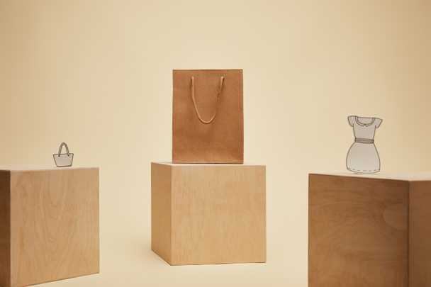 paper shopping bag, paper bag and paper dress on wooden cubes isolated on beige  - Zdjęcie, obraz