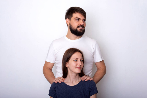Portrait of a young couple in profile. Shooting in studio on a light background. Copy space - Фото, изображение