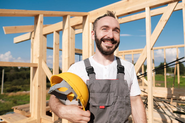 The man is a builder on the roof of a wooden frame house. - Photo, image