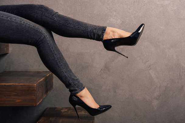 женские ноги в джинсах и туфлях на высоком каблуке на деревянной консольной лестнице
. - Фото, изображение
