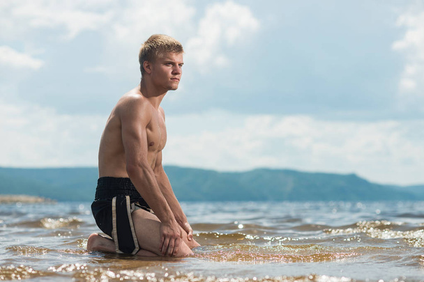 Man meditates on the beach after a workout. - Φωτογραφία, εικόνα