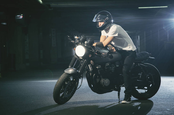 Un retrato de un motociclista en una motocicleta en un estacionamiento
. - Foto, Imagen