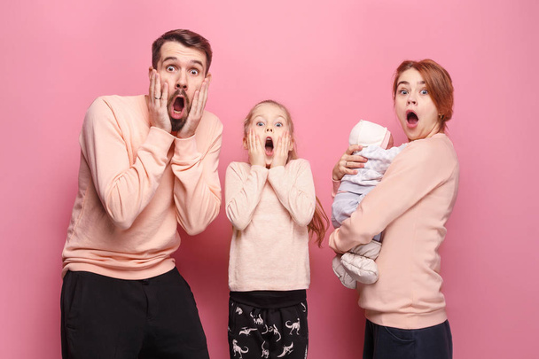 Surprised young family looking at camera on pink - Photo, Image