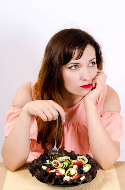 Young beautiful woman dreams of losing weight and eats vegetable salad - Photo, Image