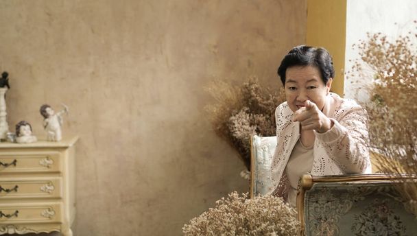 アジアの年配の女性が美しい高級インテリア部屋トスカーナ ビンテージ スタイルで座る - 写真・画像