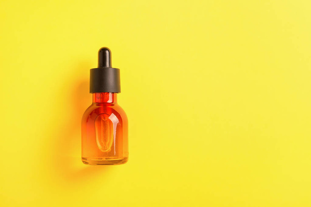 Glazen fles voor cosmetica, serums en oliën met een pipet op een gele achtergrond. - Foto, afbeelding