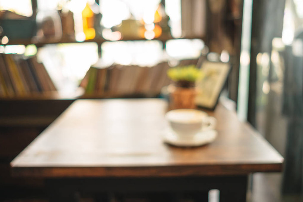 concetto astratto di sfocatura. tazza di caffè con piante e cornice posto sulla parte superiore del tavolo in legno in soggiorno ha sfondo libreria
 - Foto, immagini