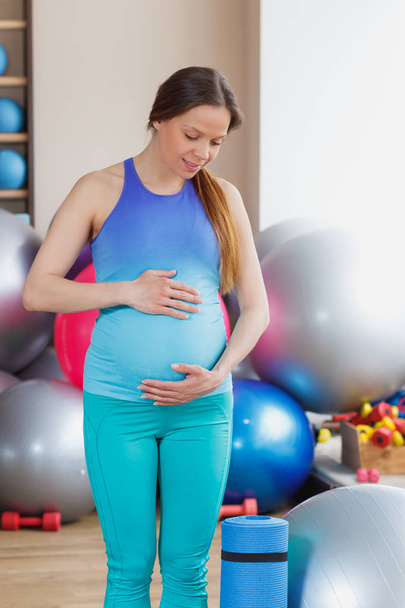 Pregnant woman with a mat in the gym. soft focus - Photo, Image