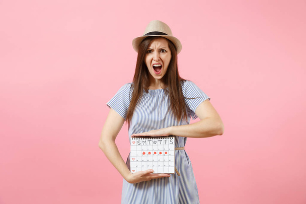 Ritratto donna malata triste in abito blu che tiene il calendario dei periodi per controllare i giorni mestruali mettere mano sulla pancia isolata su sfondo rosa. Concetto medico, sanitario, ginecologico. Copia spazio
 - Foto, immagini