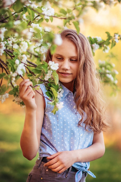Portrait of a beautiful smiling girl with beautiful long hair in spring garden. - 写真・画像