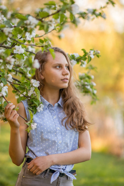 Porträt eines schönen lächelnden Mädchens mit schönen langen Haaren im Frühlingsgarten. - Foto, Bild