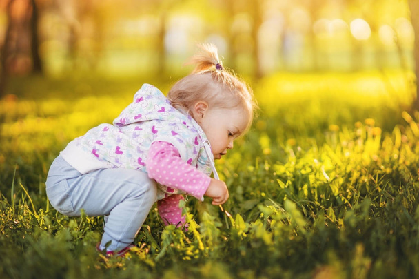 Little cute and cheerful baby girl, blonde girl, walking in a Sunny garden. - Foto, afbeelding