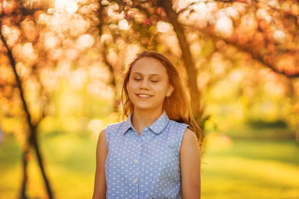 Retrato de una hermosa chica sonriente con hermoso pelo largo en el jardín de primavera
. - Foto, imagen