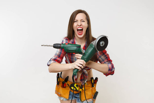 Energy handyman woman in gloves, noise insulated headphones, kit tools belt full of instruments holding power saw electric drill isolated on white background. Female in male work. Renovation concept - Foto, Imagem