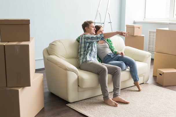 Just moved young couple on sofa planning interior in a new house. - Photo, Image
