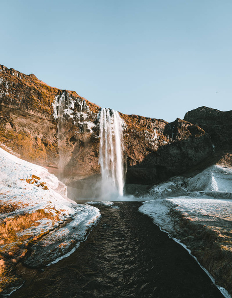 Wonderful landscape from Seljalandsfoss Waterfall in Iceland on a clear day with blue sky and snow. - Fotó, kép