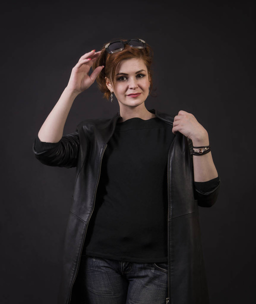 Emotional brunette posing in the Studio in a leather cloak.Isolated image on a dark background. - Foto, imagen
