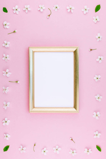 Creative flat lay concept top view of blank frame mock up and cherry tree flowers on pastel millennial pink background with copy space in minimal style, template for lettering, text or design - Photo, Image