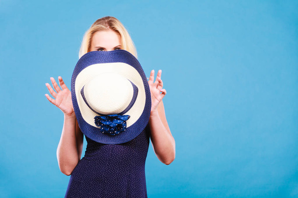 Summer trendy fashionable outfit ideas concept. Blonde attractive woman wearing short blue cocktail dress holding sun hat - Fotografie, Obrázek