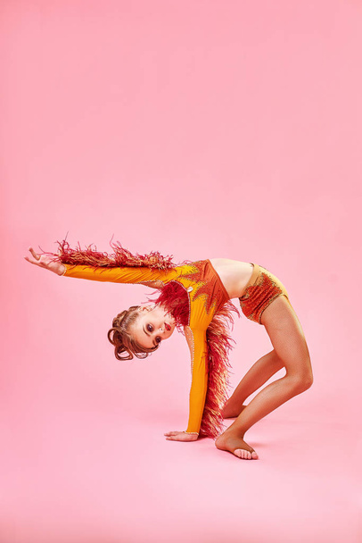 Contemporary dance. A little girl performs a complex acrobatic dance. Modern dance on a bright colorful background. - Foto, Imagen