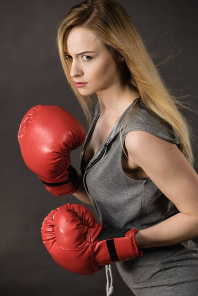 Mulher sensual jovem, menina atraente loira vestindo luvas de boxe soco vermelho posando. Esporte fitness e conceito de potência
. - Foto, Imagem