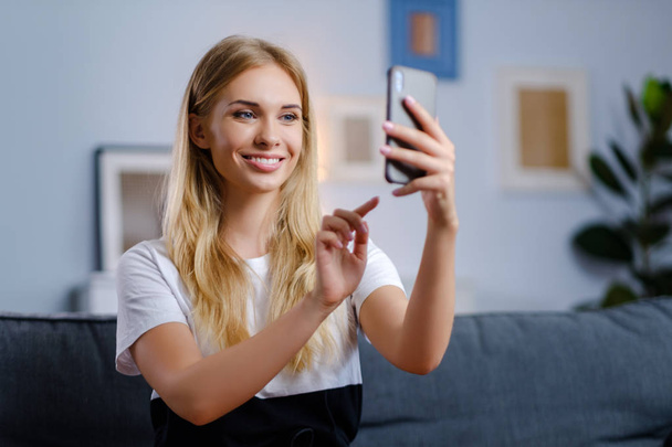 Beautiful woman using her smartphone in the living room - Foto, afbeelding