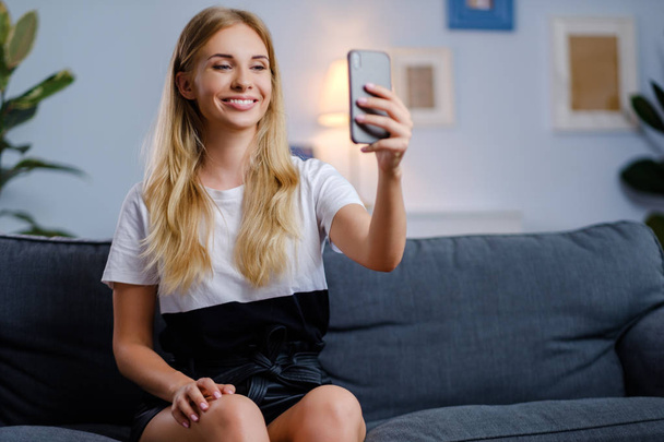 Beautiful woman using her smartphone in the living room - Photo, Image