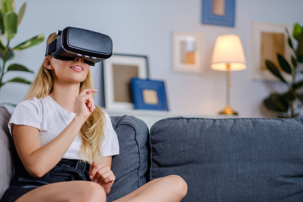Attractive young woman in VR headset gesturing and smiling - Φωτογραφία, εικόνα