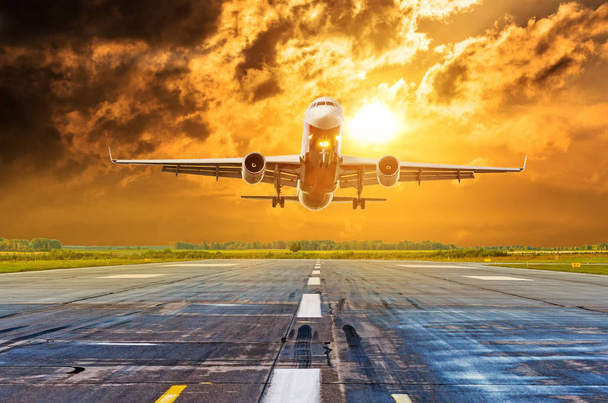 Commerciële vliegtuig vliegen van start-en landingsbaan luchthaven boven dramatische wolken - Foto, afbeelding