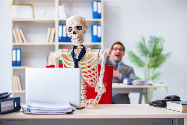 Empresario trabajando con el esqueleto en la oficina - Foto, imagen