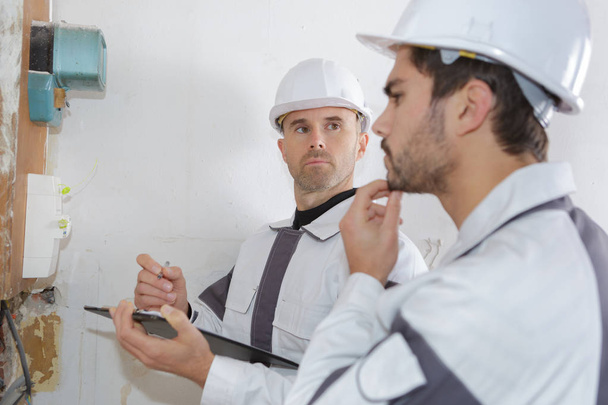 electrician and apprentice solving an issue from an industrial panel - Фото, изображение