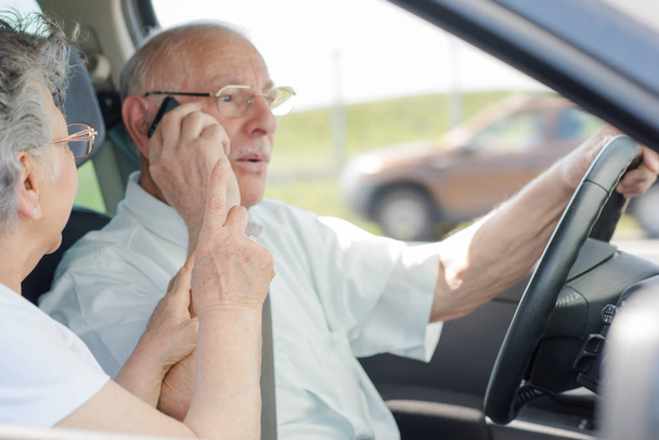 Senior zakenman rijden tijdens het gebruik van de telefoon - Foto, afbeelding
