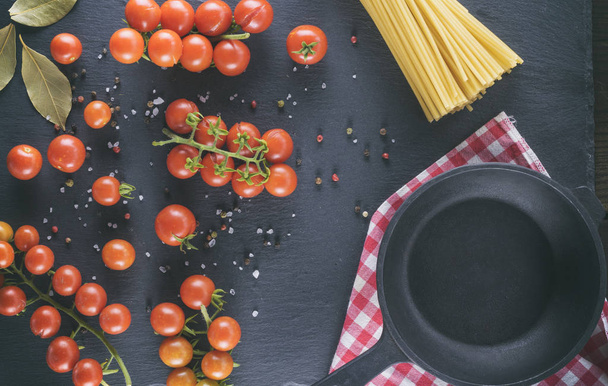 пустой чугун круглая сковорода и спелые красные помидоры черри, вид сверху
 - Фото, изображение