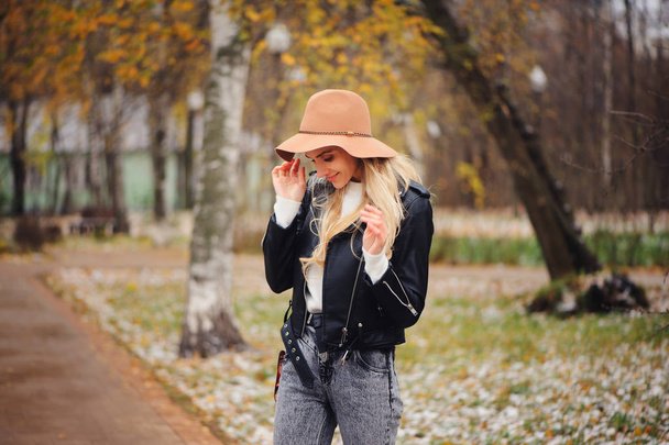 fashion autumn portrait of young happy woman walking outdoor in fall park in hat and leather jacket - Foto, Imagem