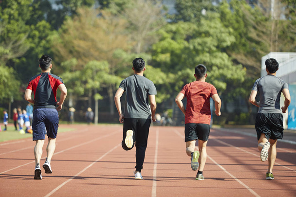 young asian adult athletes running training on track, rear view. - Photo, Image