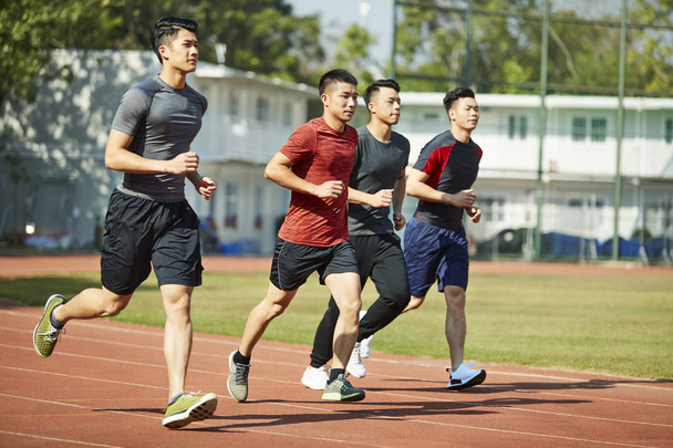 jóvenes asiáticos adultos atletas corriendo entrenamiento en pista, vista lateral
. - Foto, Imagen