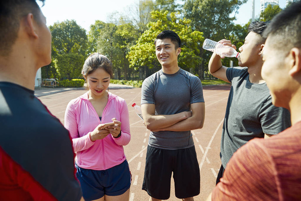jovem asiático adultos atletas relaxante falando na pista depois de exercitar
. - Foto, Imagem