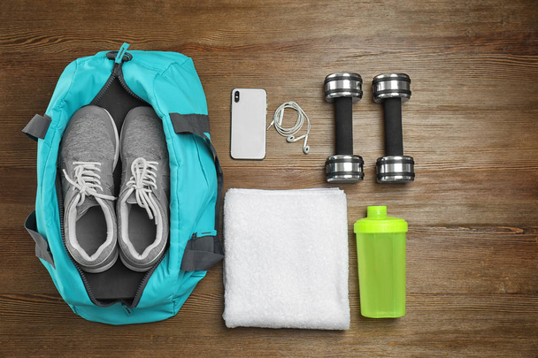 Sports bag and gym equipment on wooden background, top view - Φωτογραφία, εικόνα